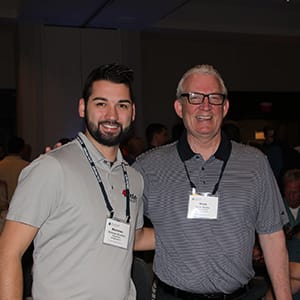 two gentleman smiling for portrait at conference