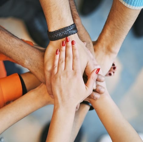 multiple people putting their hands together