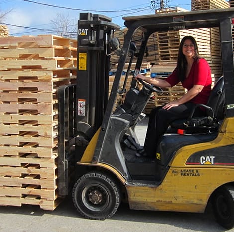 woman on machine moving wooden pallets