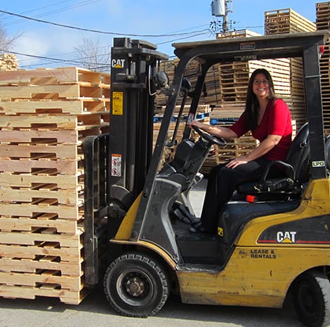 woman driving jack with pallets on it