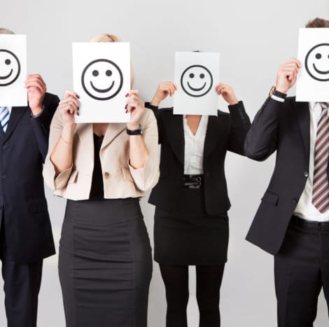 four people holding a smiley face over there face