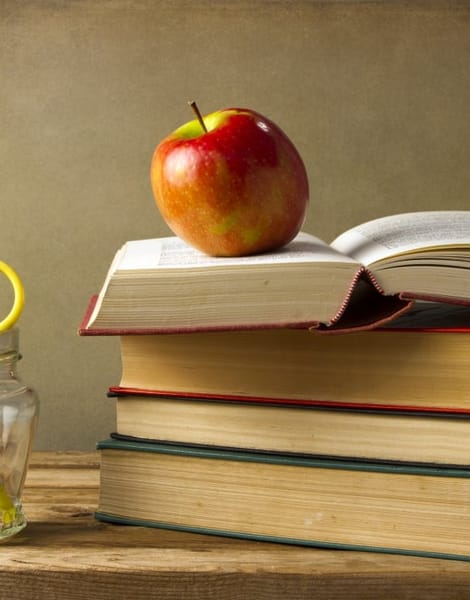 multiple school books and apple on desk