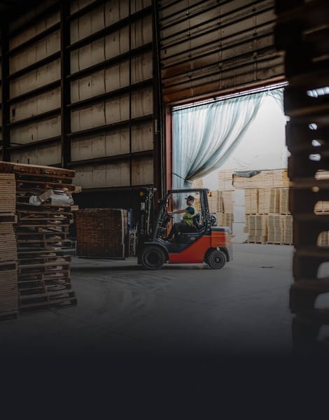 man moving wooden pallets around