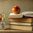 multiple school books and apple on desk